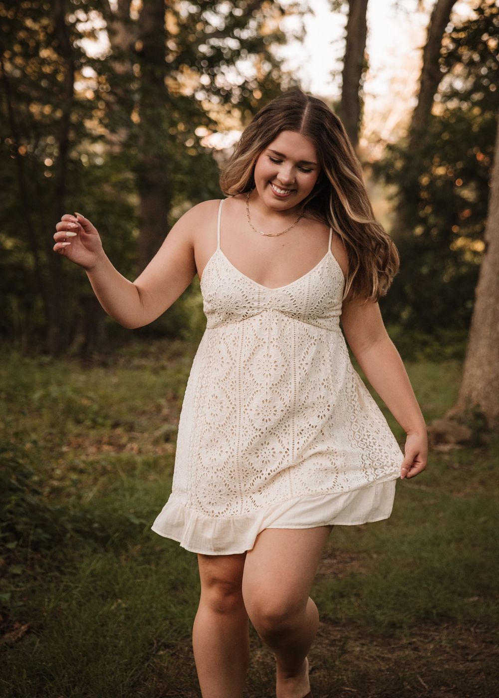 Carefree movement captured in white lace dress against natural outdoor setting.
