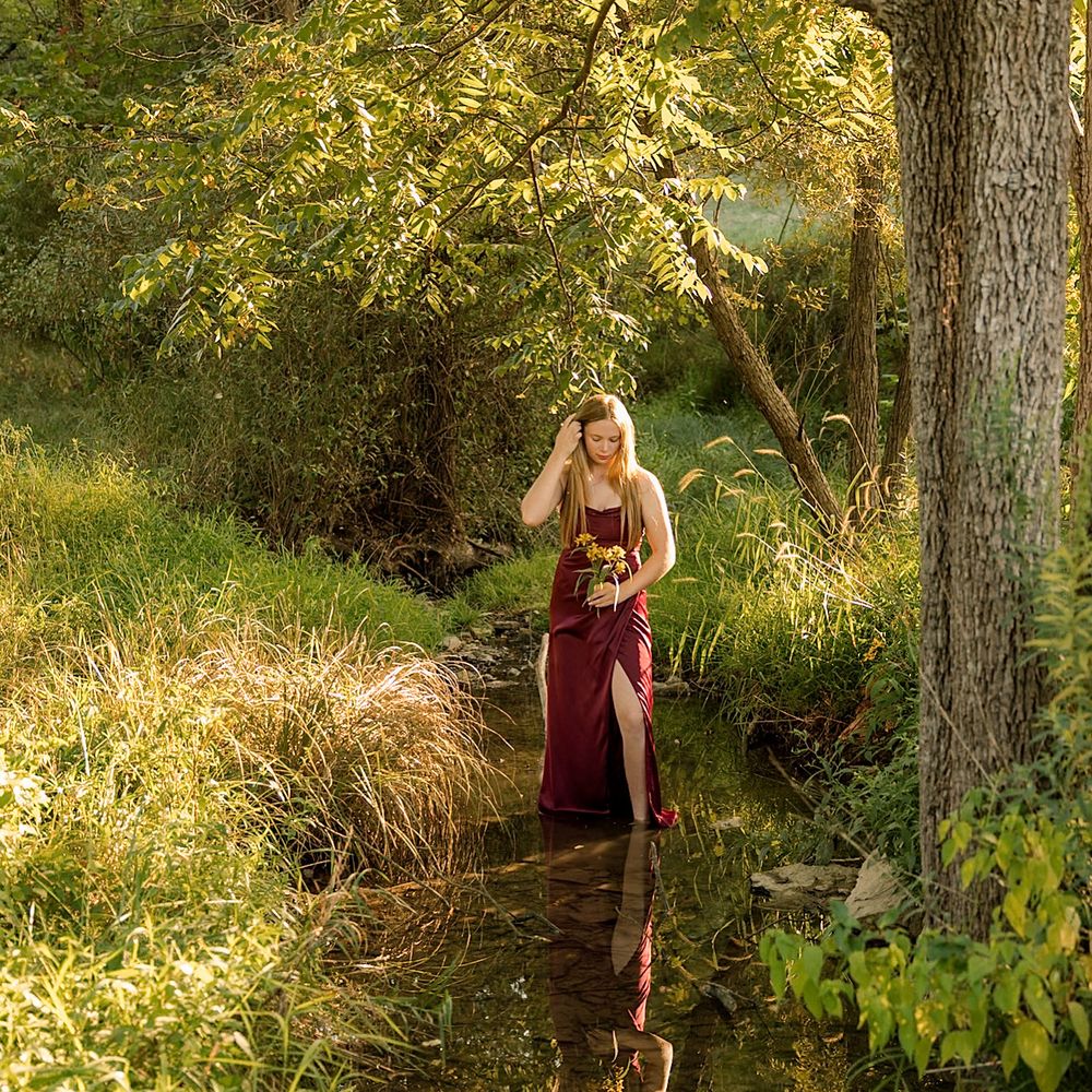 Ethereal portrait session in a wooded area with golden sunlight filtering through trees.