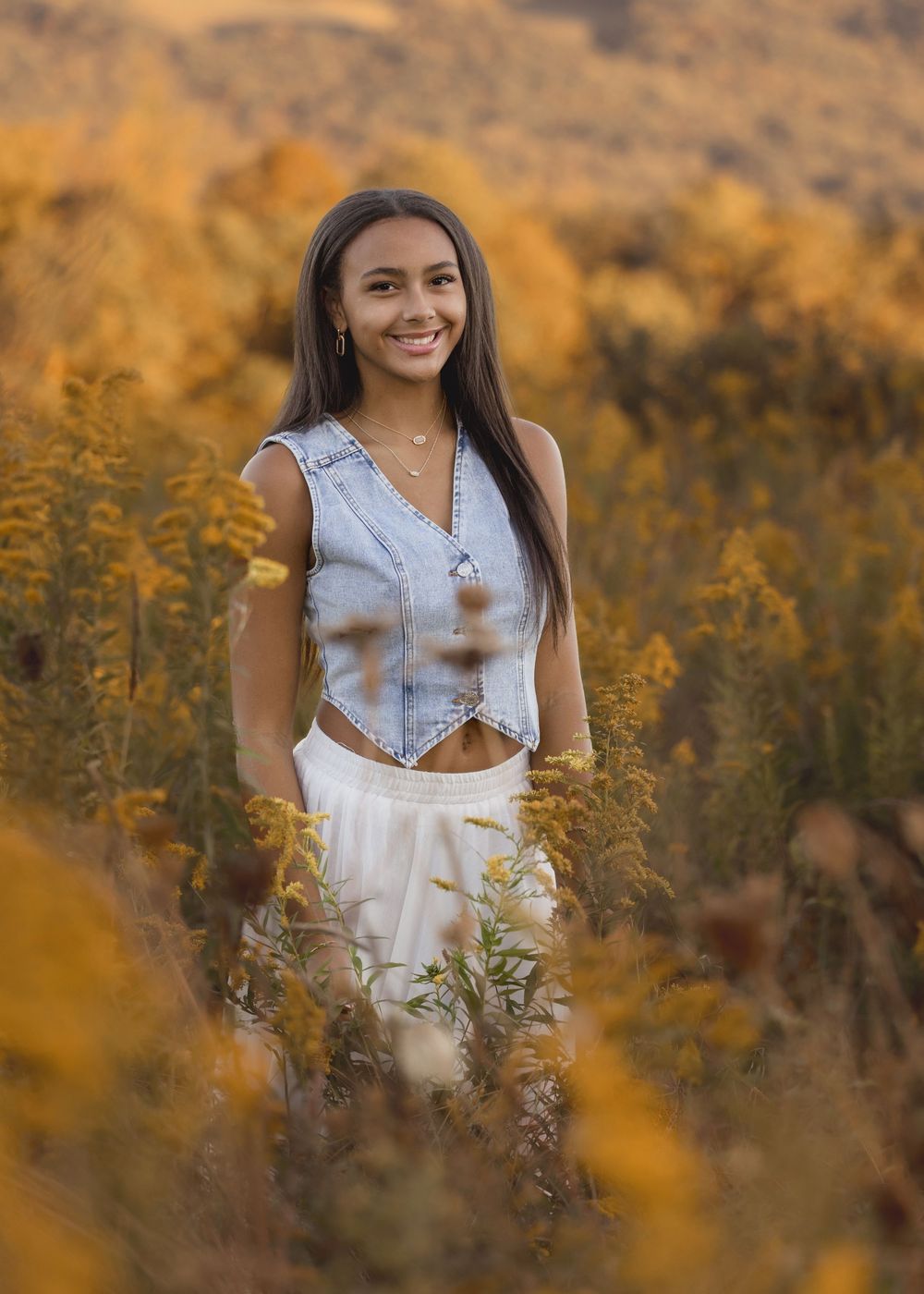Outdoor portrait series in white crop top among golden wildflowers at sunset.