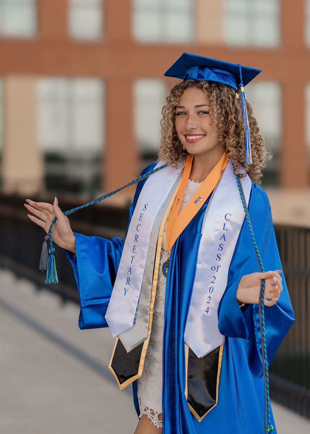 Graduate in blue cap and gown celebrates with joyful poses on campus.