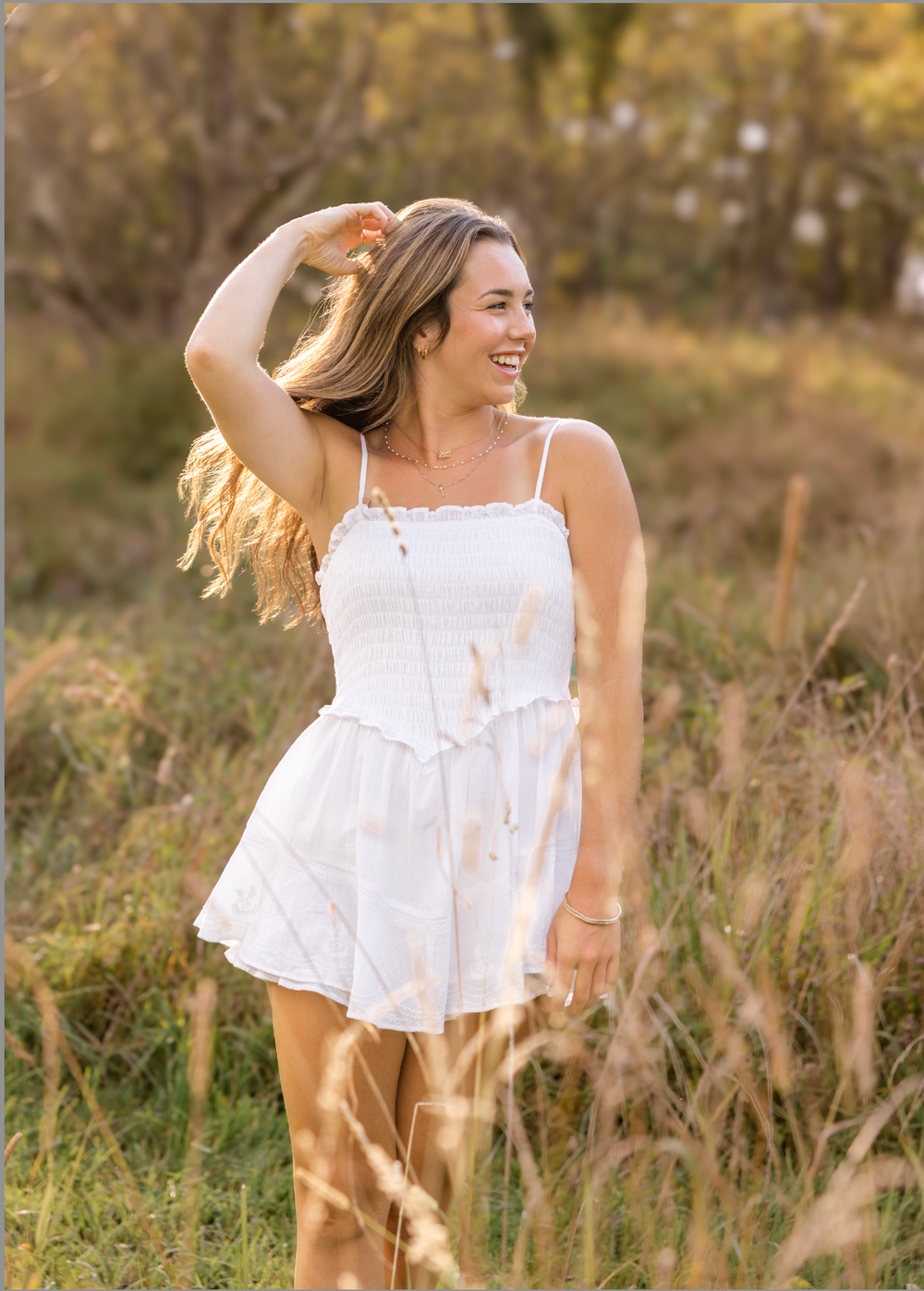 Person in flowing white summer dress twirls in a sunlit meadow during golden hour.