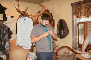 A person in a gray t-shirt stands in a room decorated with antlers and rustic decor mounted on the walls.