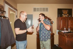 Two people having a conversation while holding beverages at an indoor gathering.