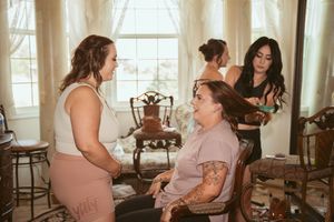 Wedding day preparation scene with multiple people in pink dresses getting ready in a bright sunlit room.
