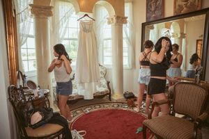 Group getting ready in an elegant room with ornate mirrors and red carpeting.