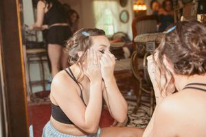 Wedding party members gathering in an elegant bridal suite with white and teal dresses.