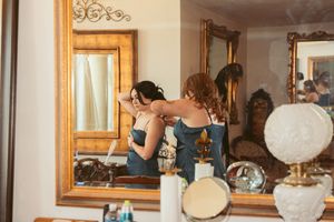 Wedding party getting ready in a sunlit room with vintage decor and mirrors.