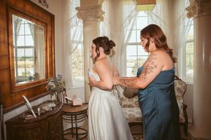 Bright sunlit room with tall windows and elegant columns where pre-event preparations are happening.