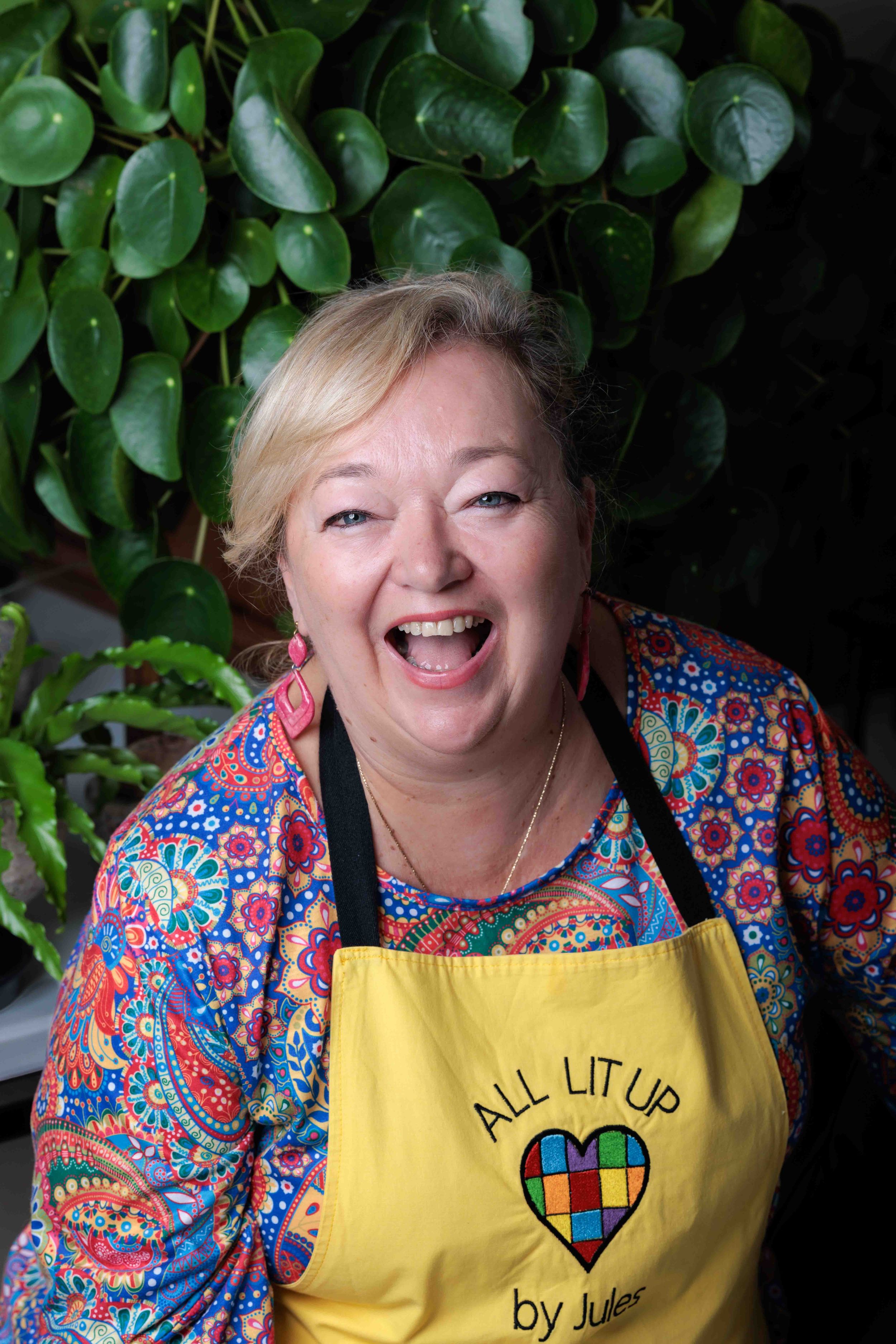 Woman wearing colourful clothes and apron with logo laughing
