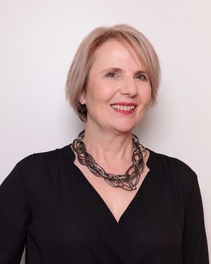 Headshot of woman wearing chunky necklace and black top