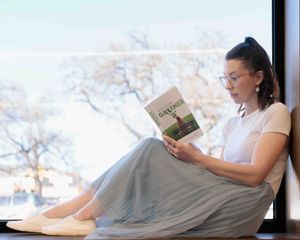Young female author reading in the window of the library
