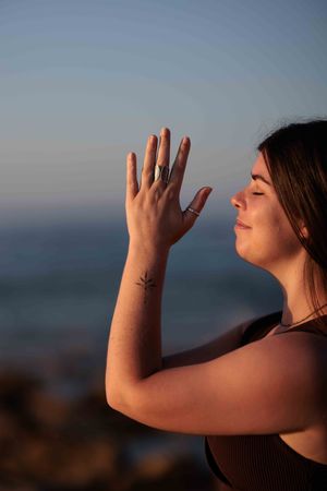 photo of young woman doing Yoga at sunrise at the beach