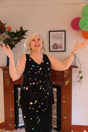 Woman celebrating throwing confetti with balloons nearby