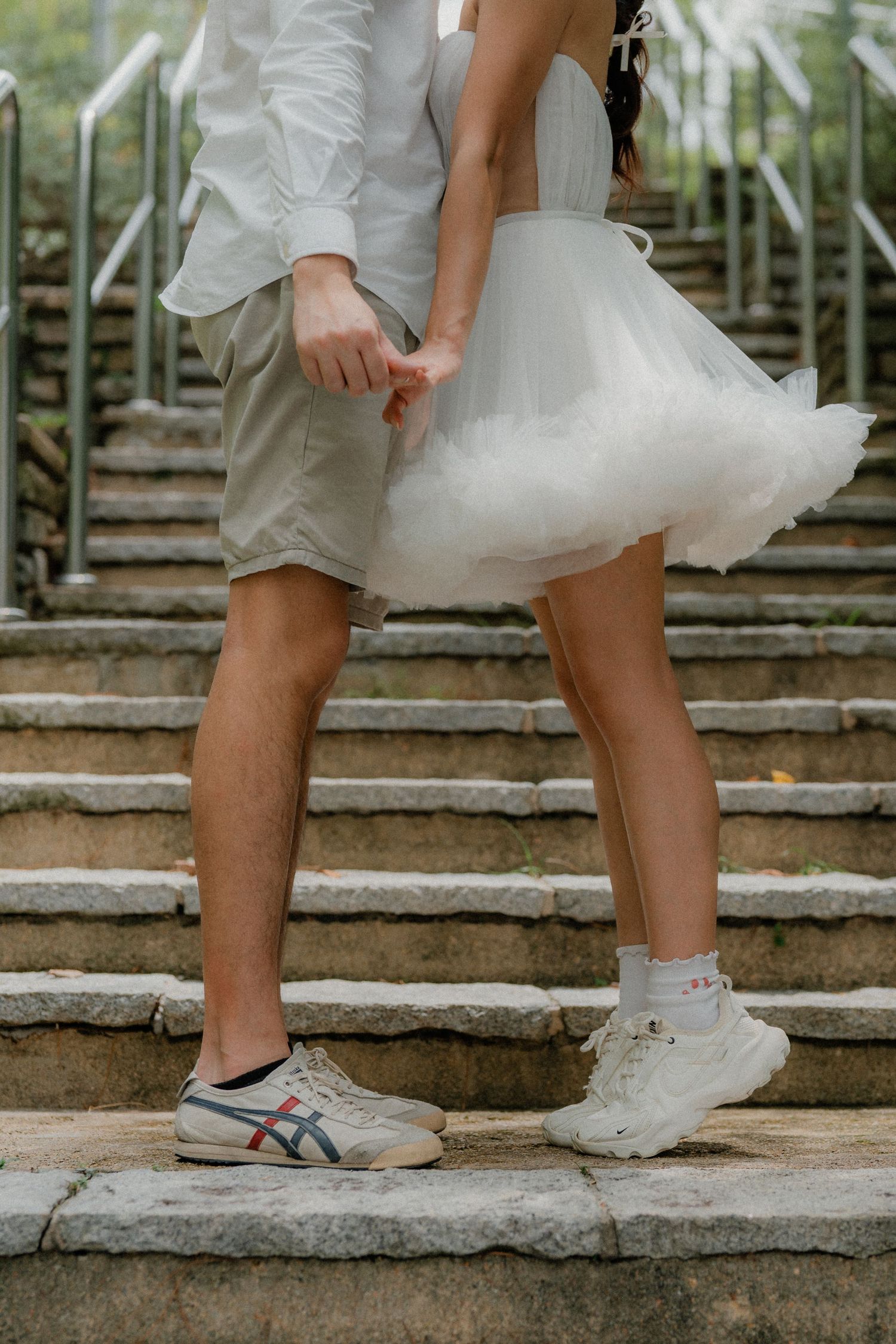 Feet in white sneakers walking down stone steps with tulle dress hem visible.