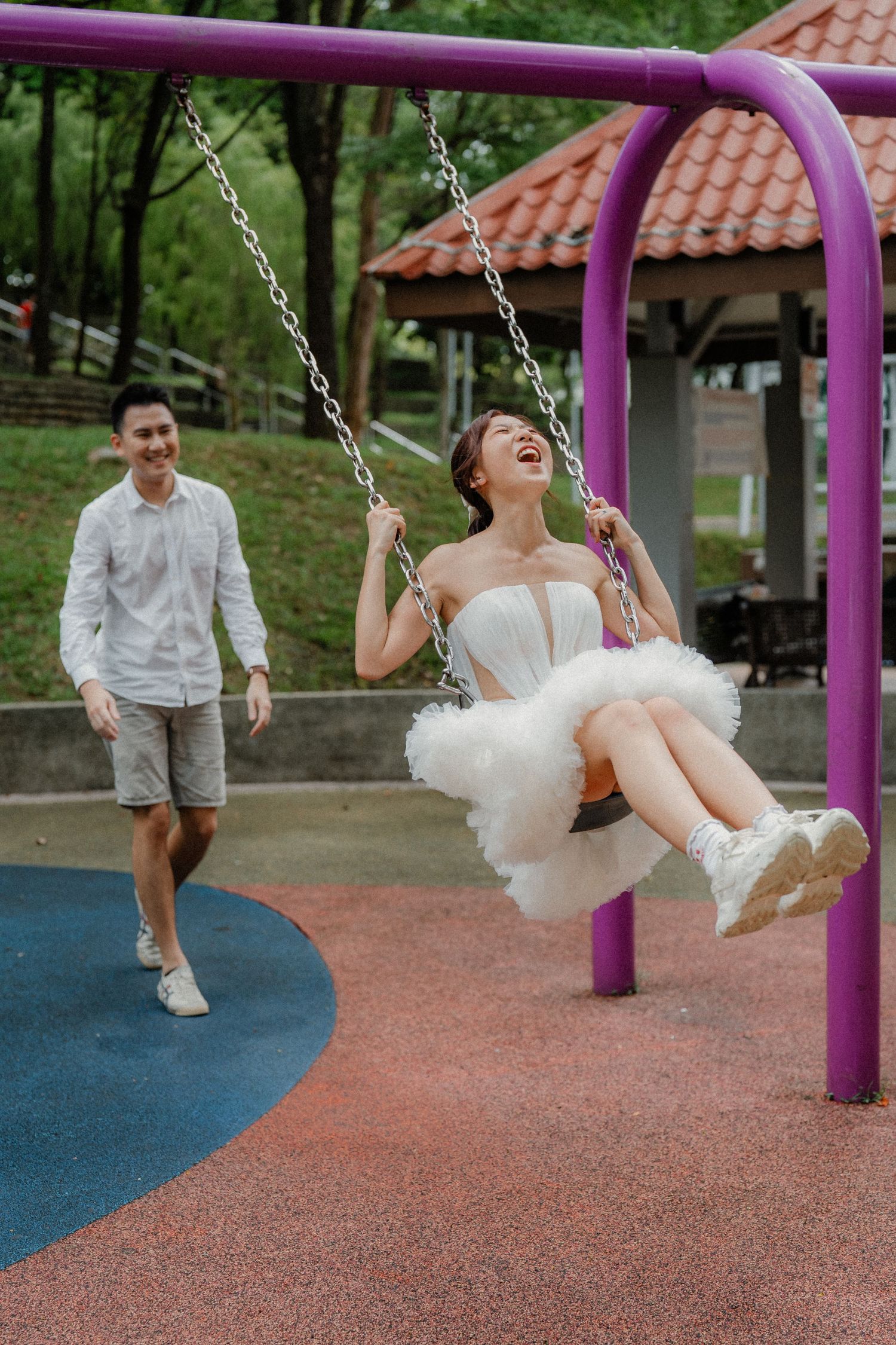 Pure happiness captured on a playground swing set with someone in a fluffy white dress enjoying the moment.