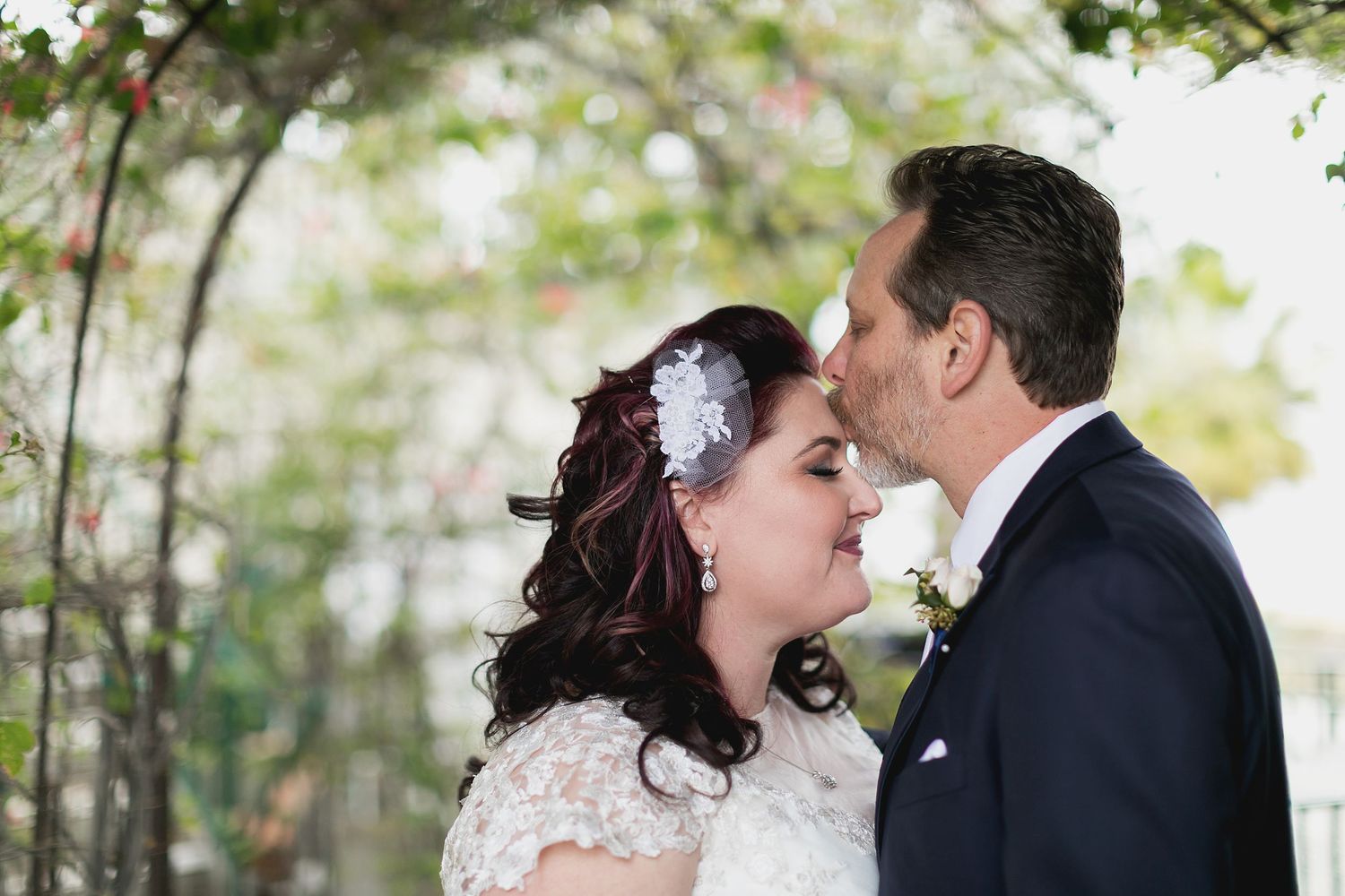 Romantic wedding photo of bride and groom sharing an intimate moment under garden archway.