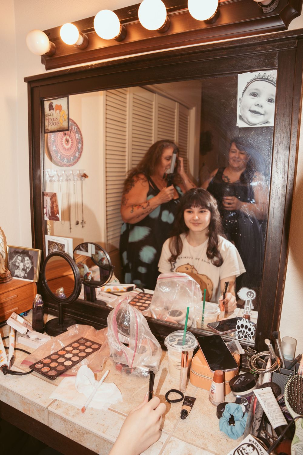 A dressing room with vanity lights where wedding preparations are taking place with makeup and accessories.