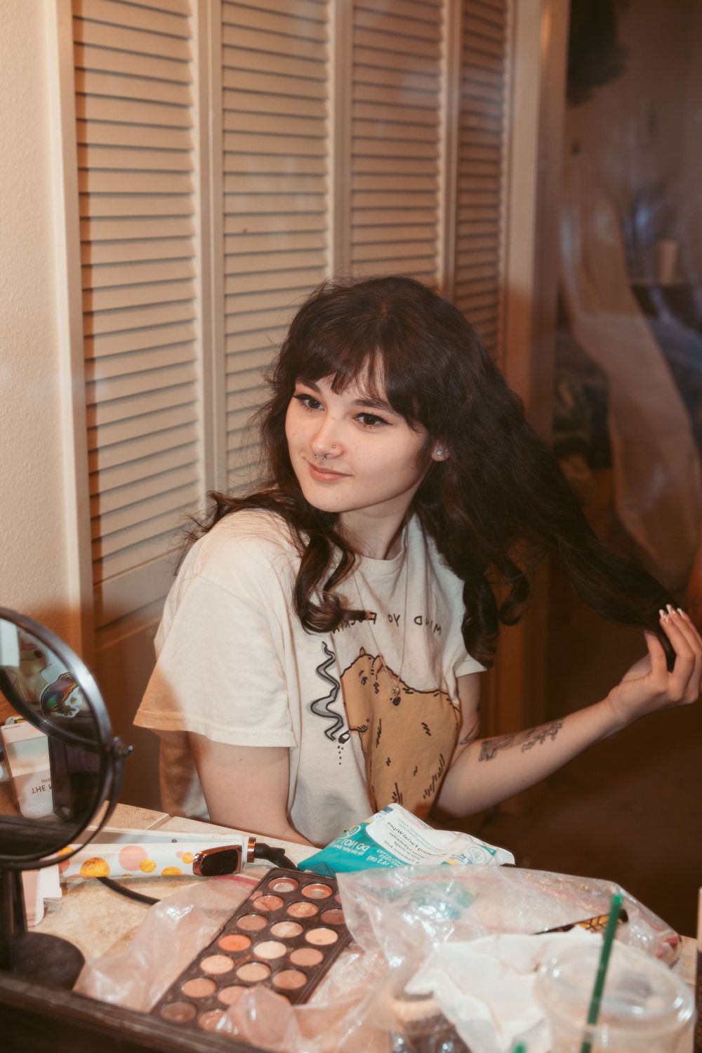 Person working with makeup and cosmetics at a table with various beauty products.