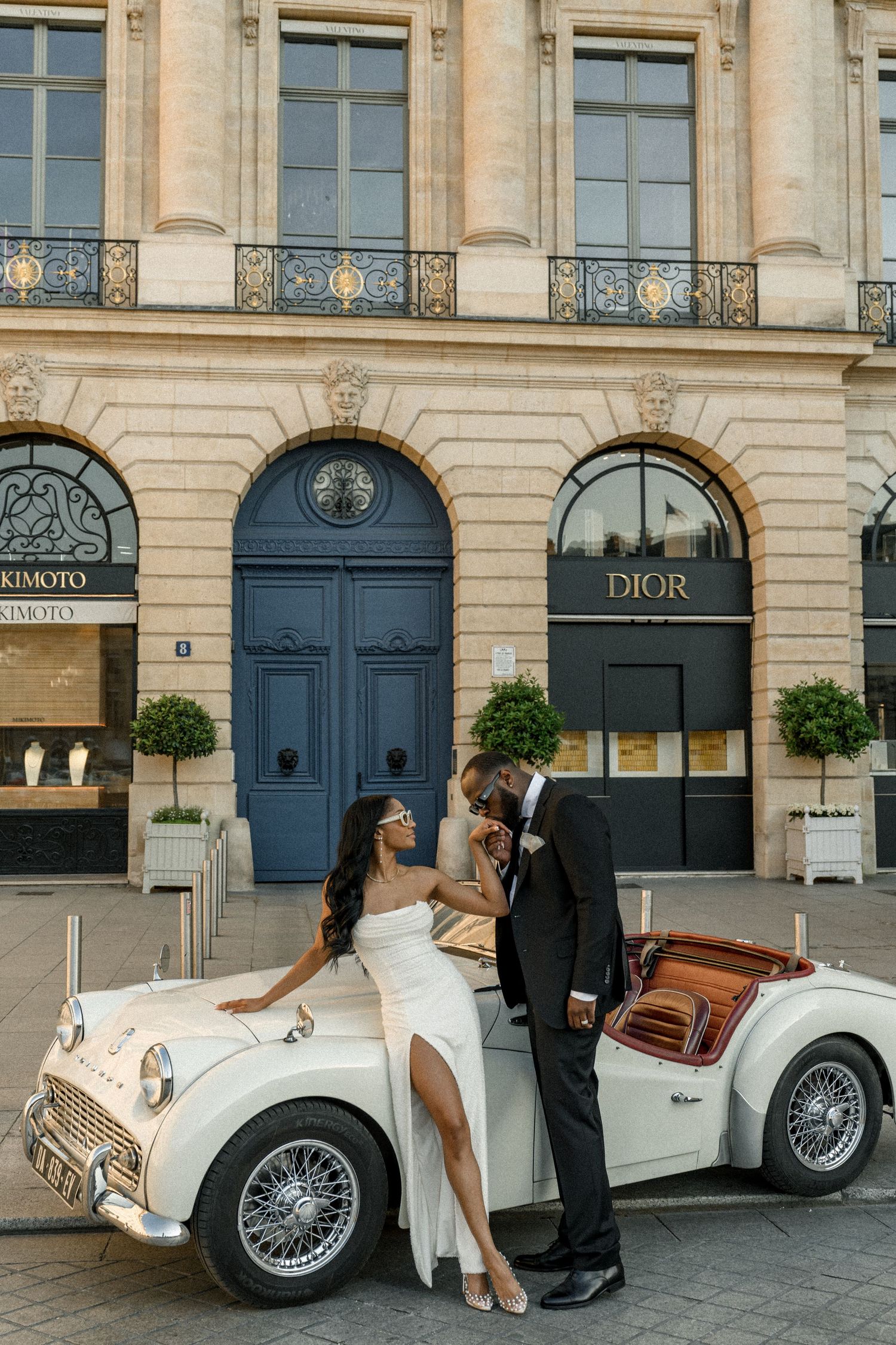 Two hands touch tenderly against a blurry cityscape backdrop, with one person wearing an elegant wristwatch.