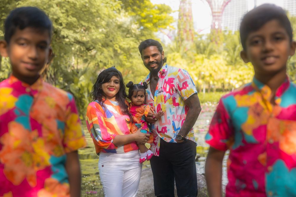 A smiling group celebrates outdoors wearing vibrant tie-dye colored clothing during a warm sunny day.