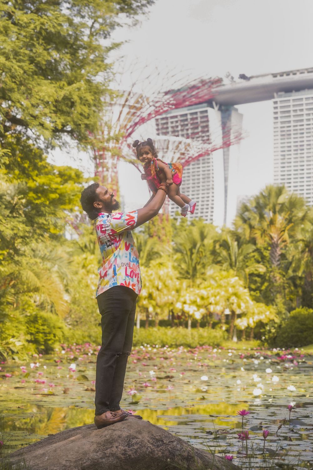 A playful moment captured at Gardens by the Bay in Singapore with the iconic Marina Bay Sands hotel visible in background.