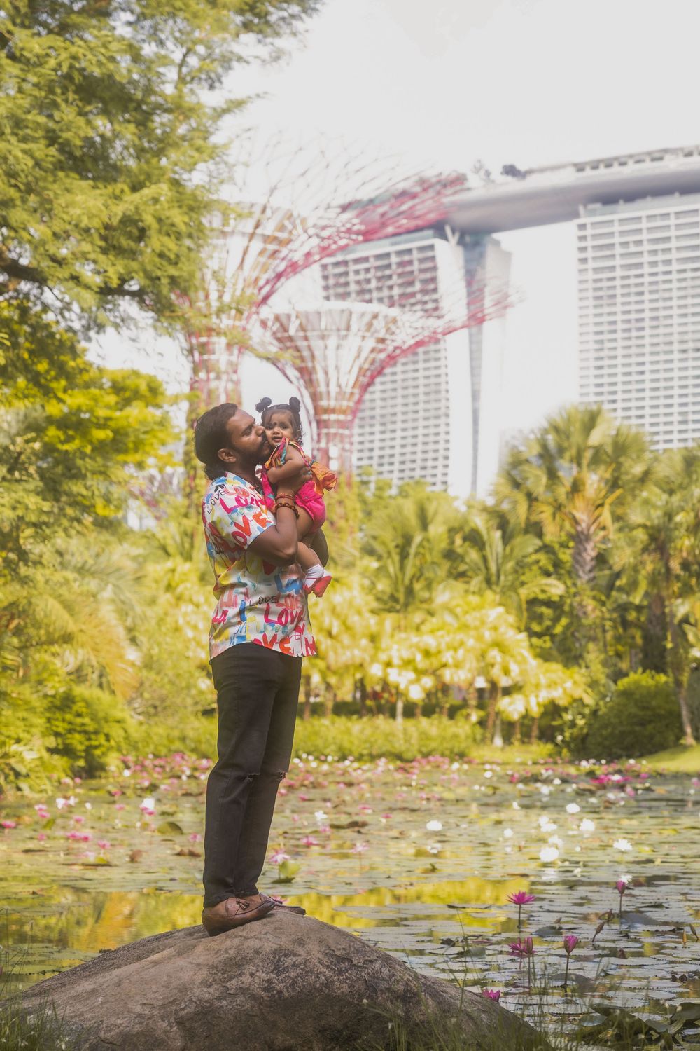 A joyful moment captured in a garden with Marina Bay Sands hotel visible in the background in Singapore.