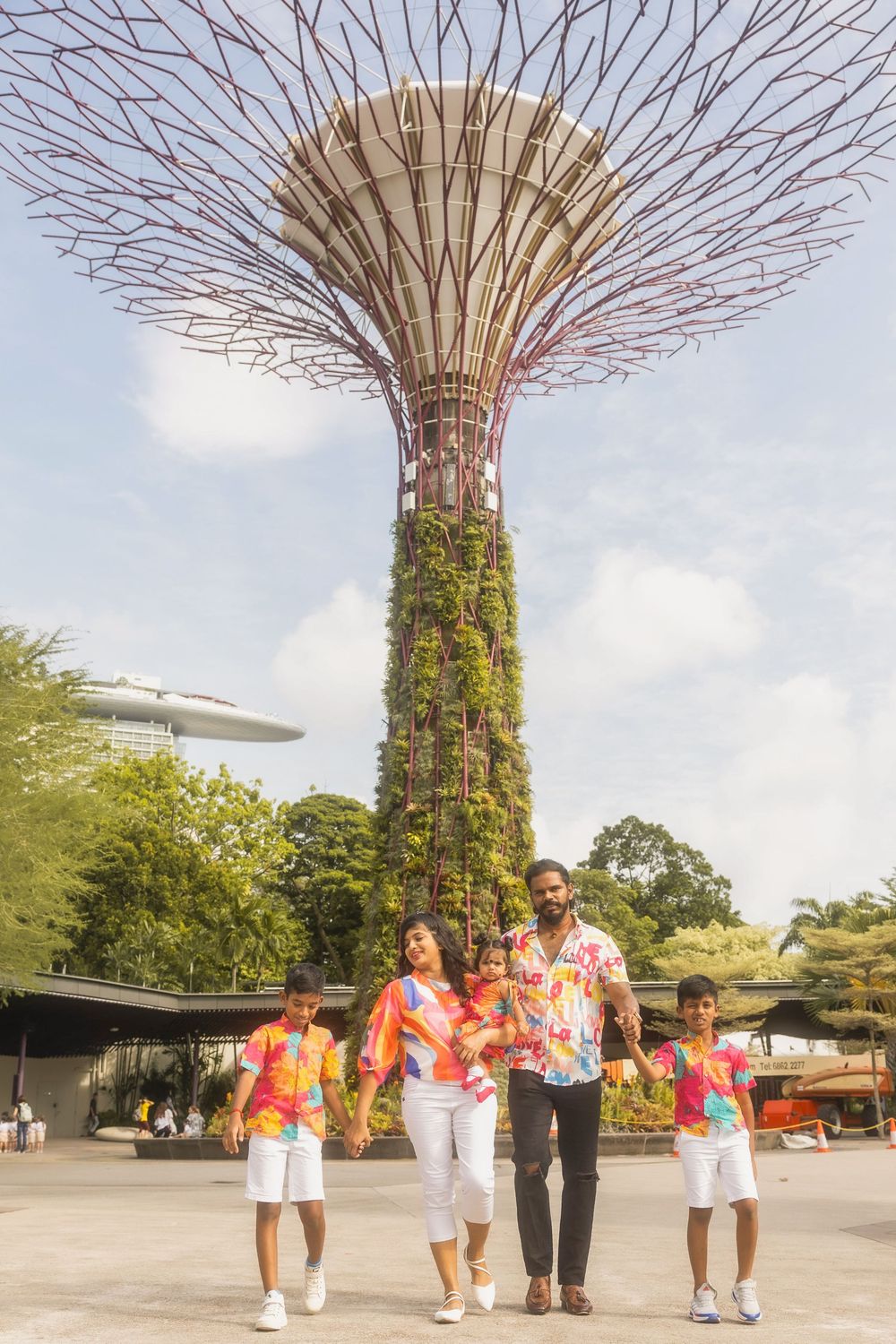 A family enjoying a day out at Singapore's Gardens by the Bay with the Super Tree Grove structure rising dramatically behind them.