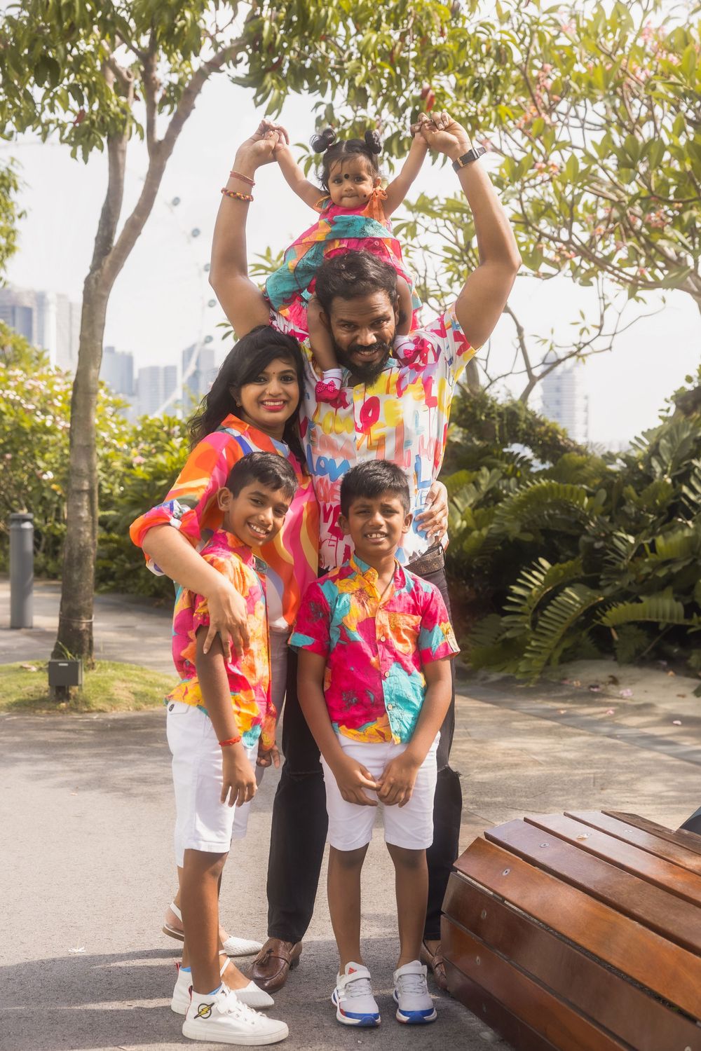 A parent and child laughing together outdoors while wearing colorful Hawaiian print shirts and white shorts.