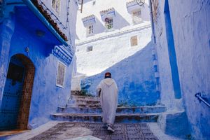 Bright blue painted walls and stairs create a striking passageway in the historic medina of Chefchaouen, Morocco.