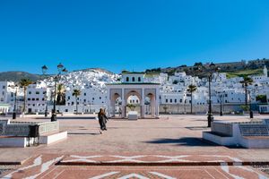 A white seaside town in Morocco down terraced hillsides along the Mediterranean coast on a bright sunny day.