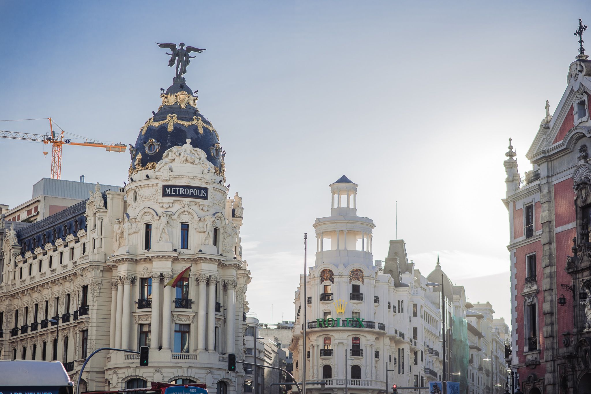 Historical buildings with ornate architecture line an urban street in Madrid, Spain with prominent domed structures.