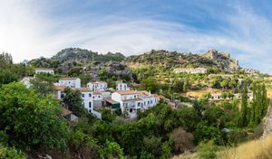 Panoramic view of white hillside houses nestled in the mountains of Seville, Spain on a sunny day.