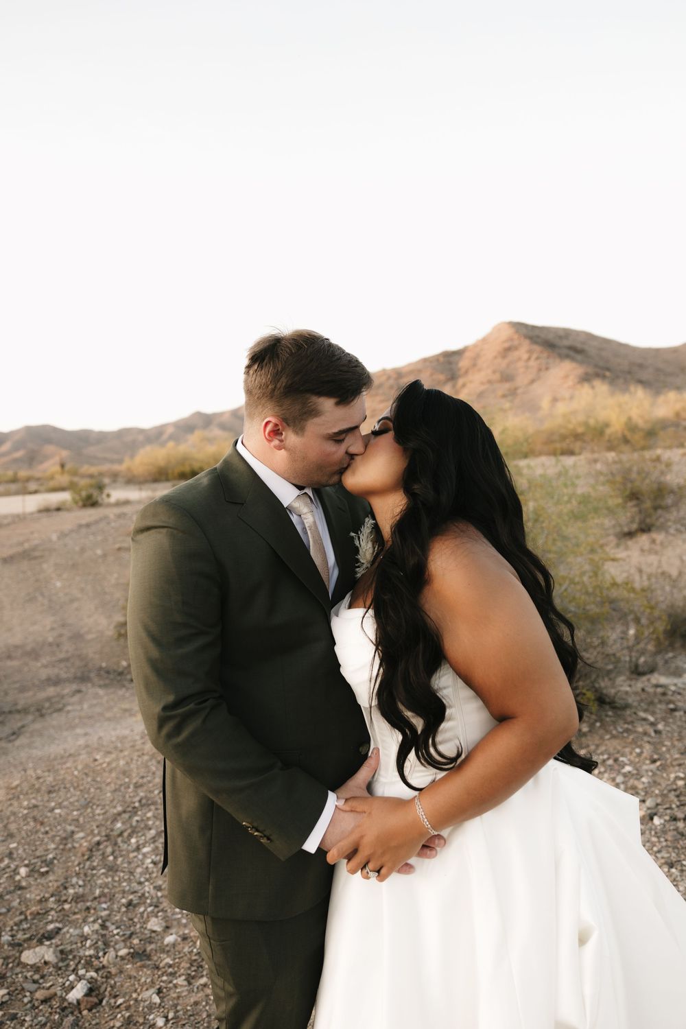 A romantic wedding photoshoot in a desert landscape with dramatic mountains in the background.