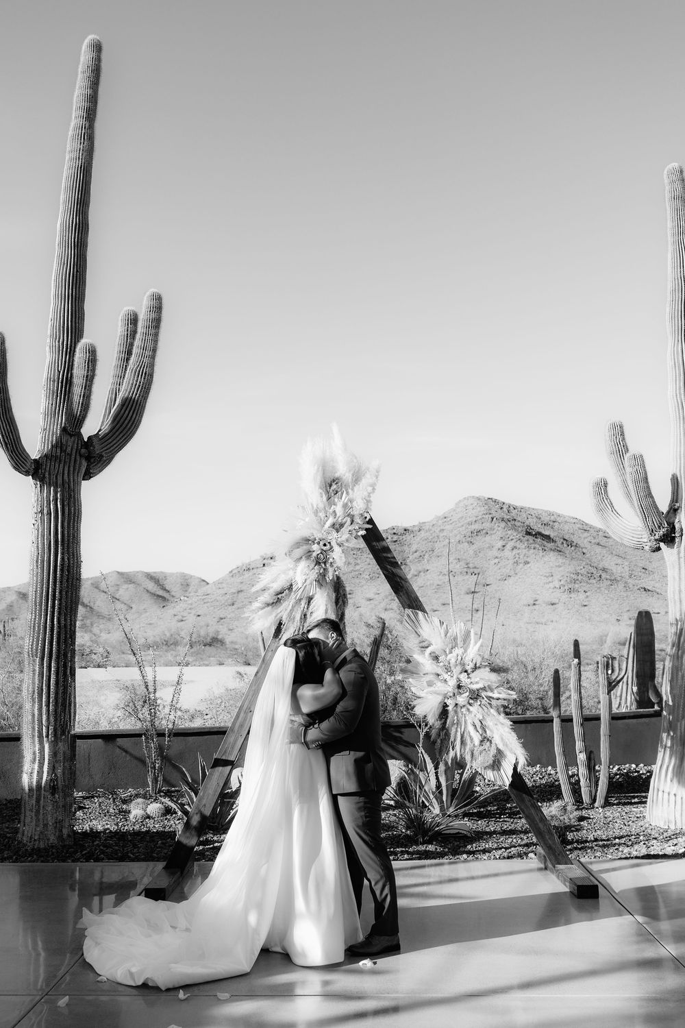 Black and white wedding photos featuring tall saguaro cacti in a desert setting.