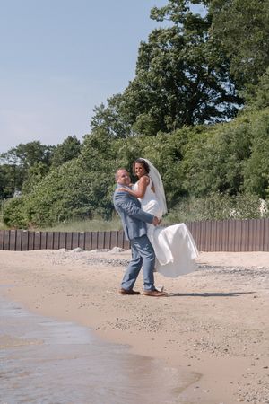 Sequence of candid photos showing two people playfully dancing on a beach near the shoreline surrounded by trees.