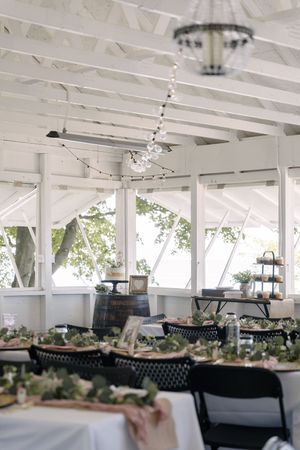 White covered outdoor reception venue with elegant table settings and hanging lights creating a romantic atmosphere.