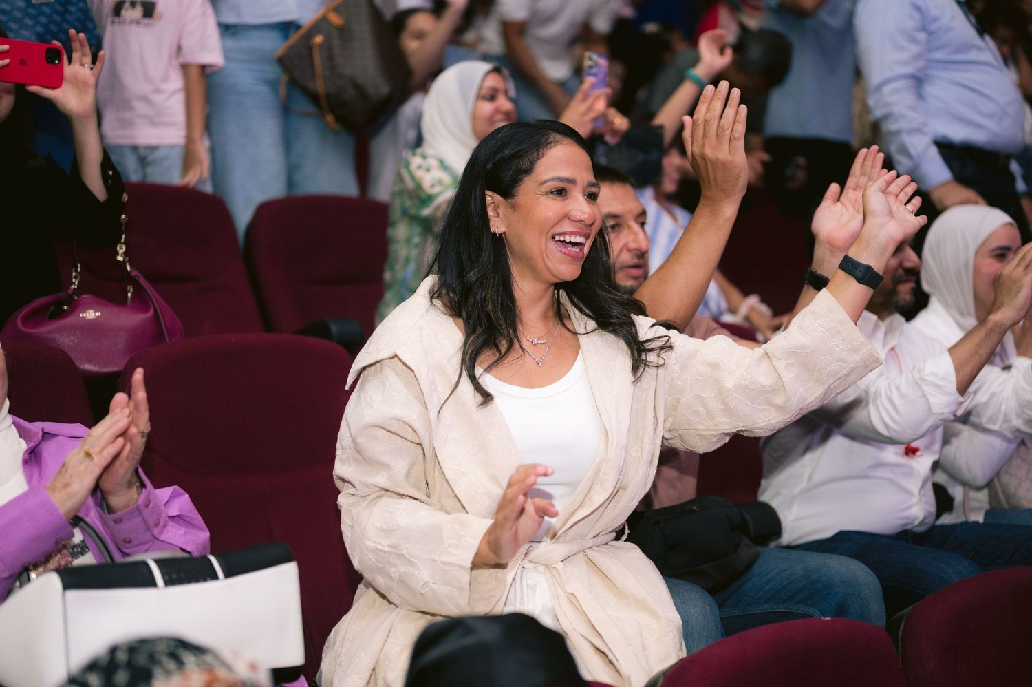Audience members in white attire react enthusiastically during a live performance event.