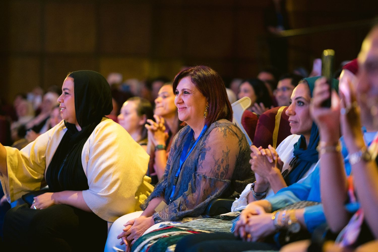 Theater audience watching a performance with expressions of joy and engagement.