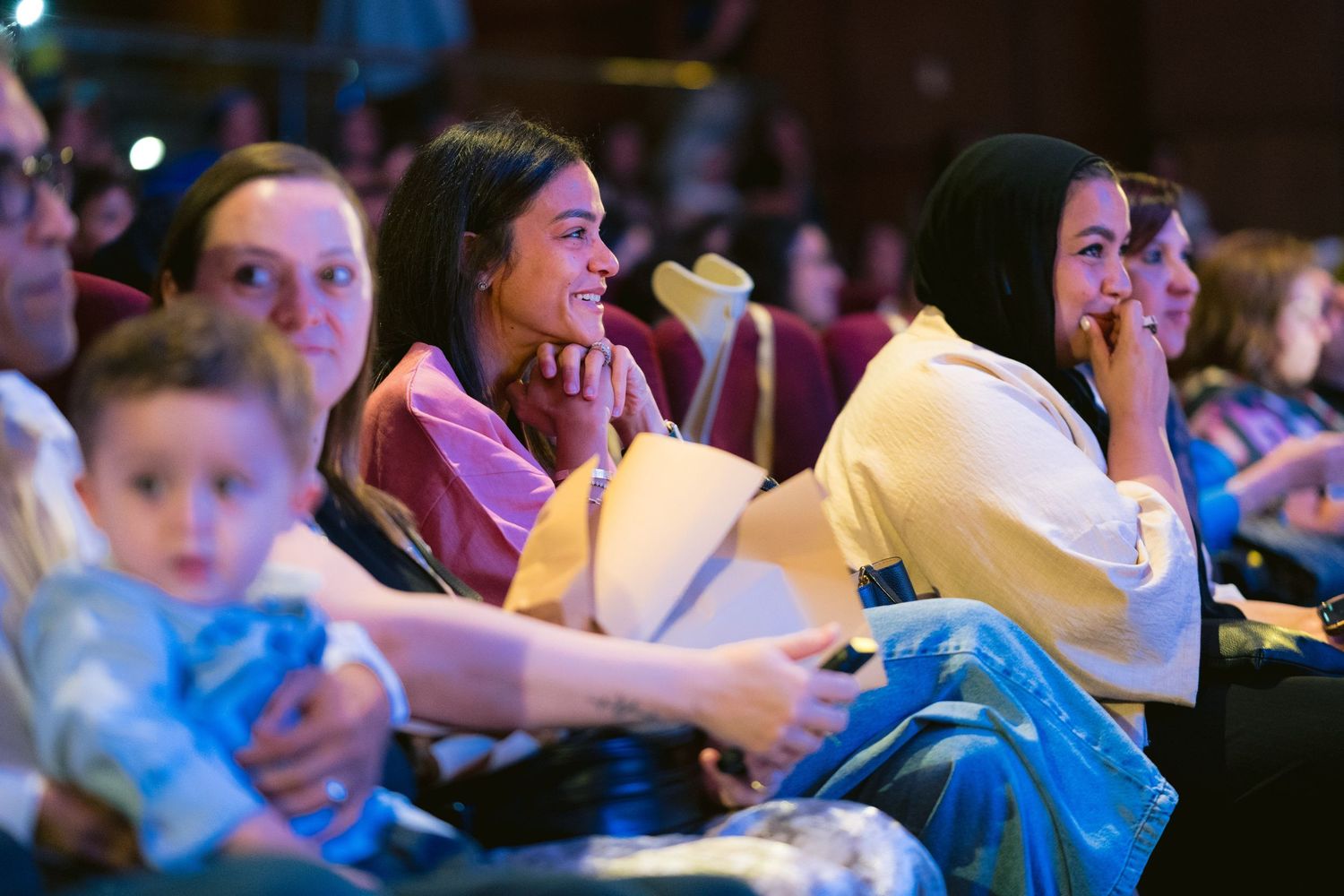 Audience members watch intently and react emotionally during a performance in a darkened theater.