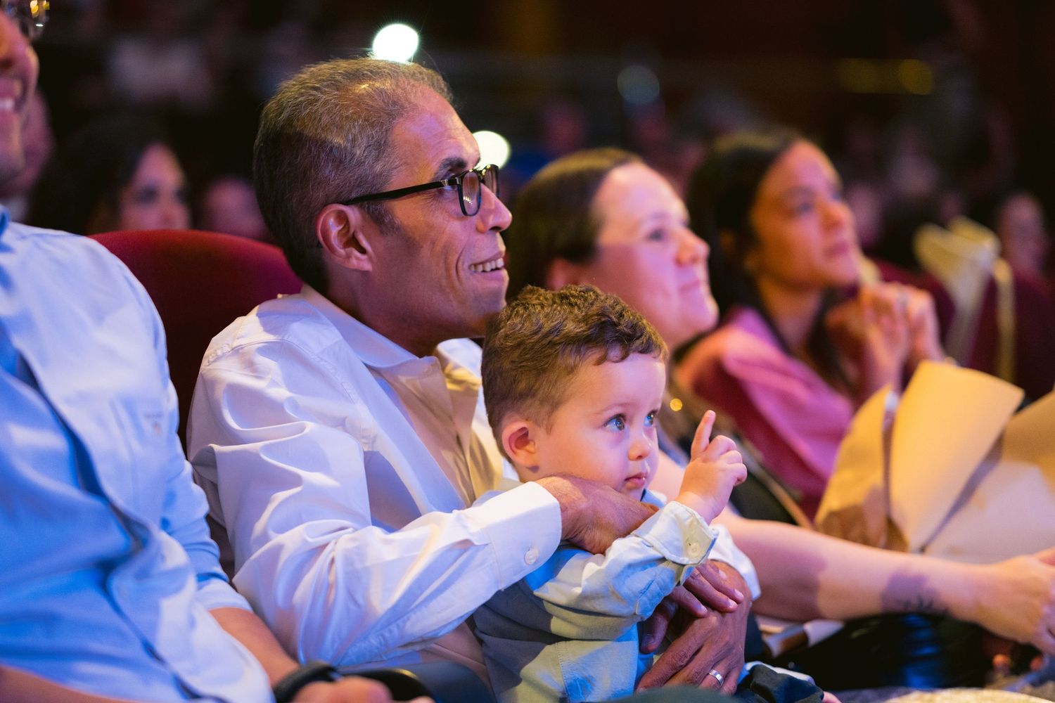 Theater audience sitting in dimly lit rows watching an engaging performance.