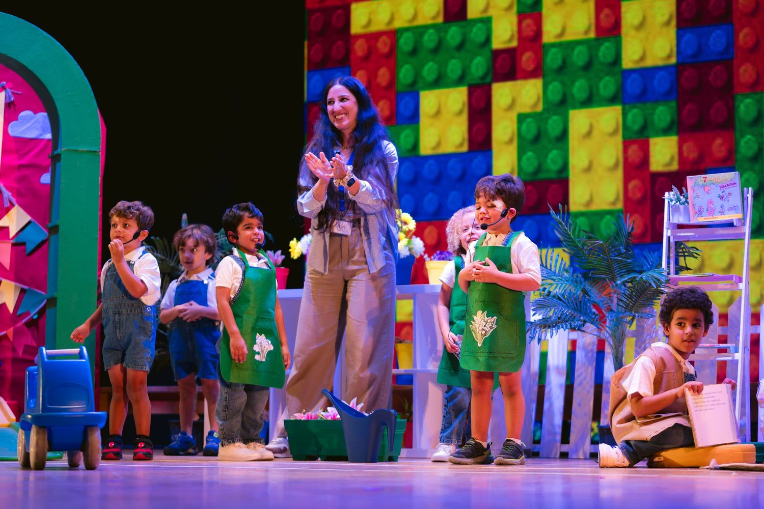 Colorful LEGO-themed stage backdrop with bright blocks and decorative elements creates a playful theatrical setting.