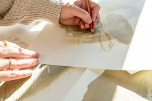 Close-up view of hands writing on note cards or index cards on a white desk surface.