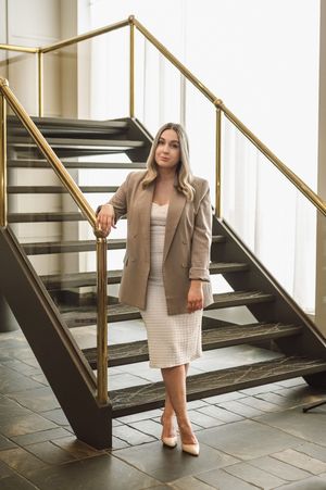 Professional photo series featuring neutral business attire and high heels posed on modern staircase with gold railings.