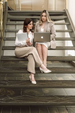 Lifestyle photography session on stone stairs featuring laptops and neutral-toned office attire.