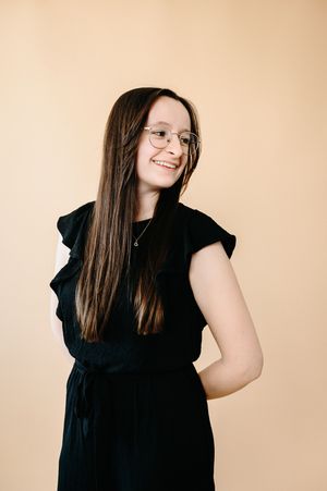 A person with long brown hair wearing a black sleeveless top poses against a beige background in a photo series.