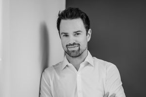 A black and white photo series of someone wearing a white dress shirt against a light background, smiling warmly.