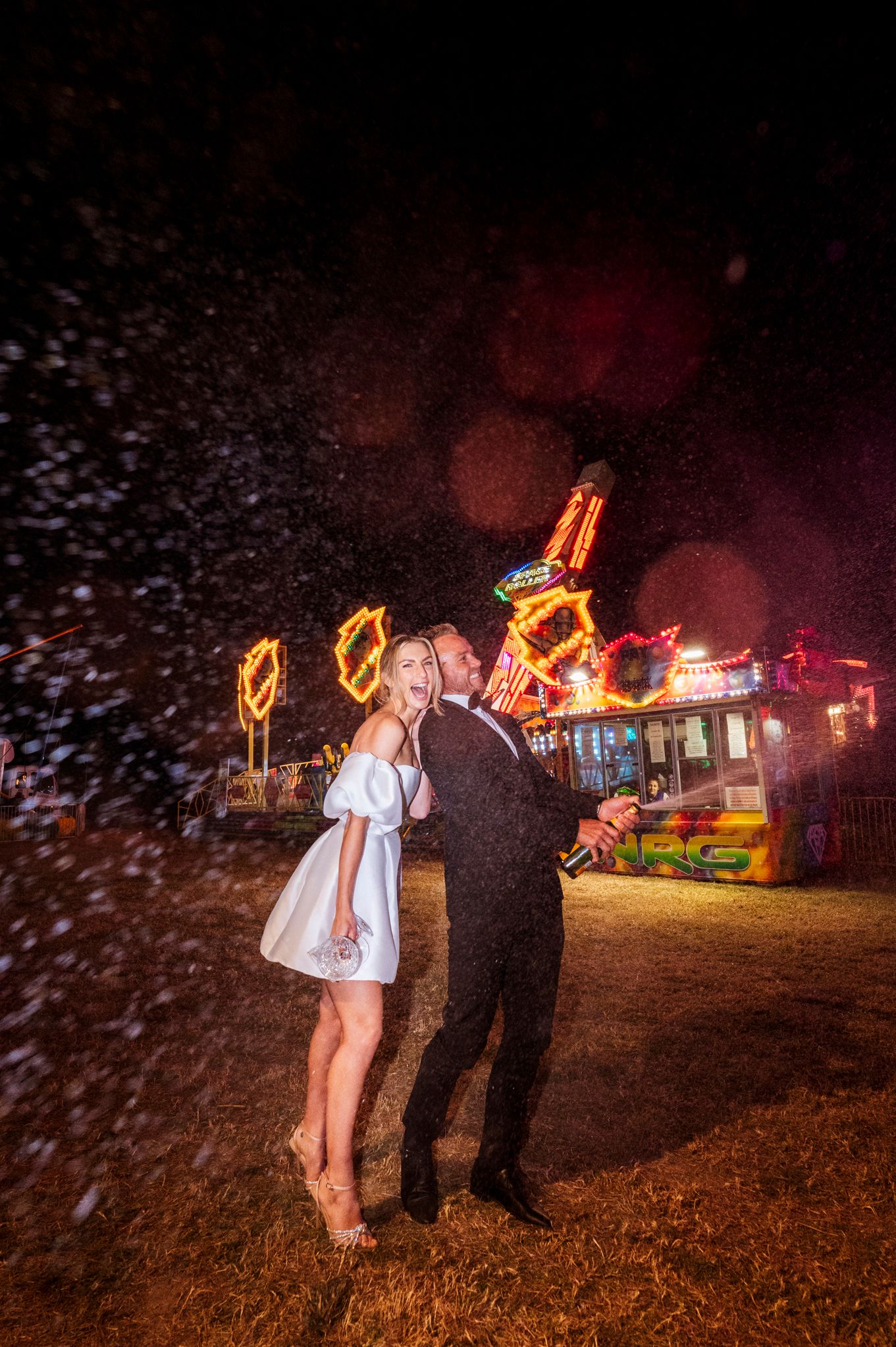 A couple dances at a carnival with glowing lights and falling snow in the background.