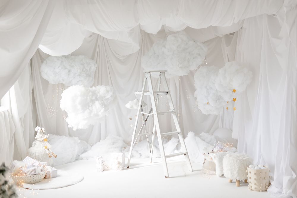 White curtains draped elegantly throughout a bright, romantic wedding ceremony venue with chairs and floral arrangements.