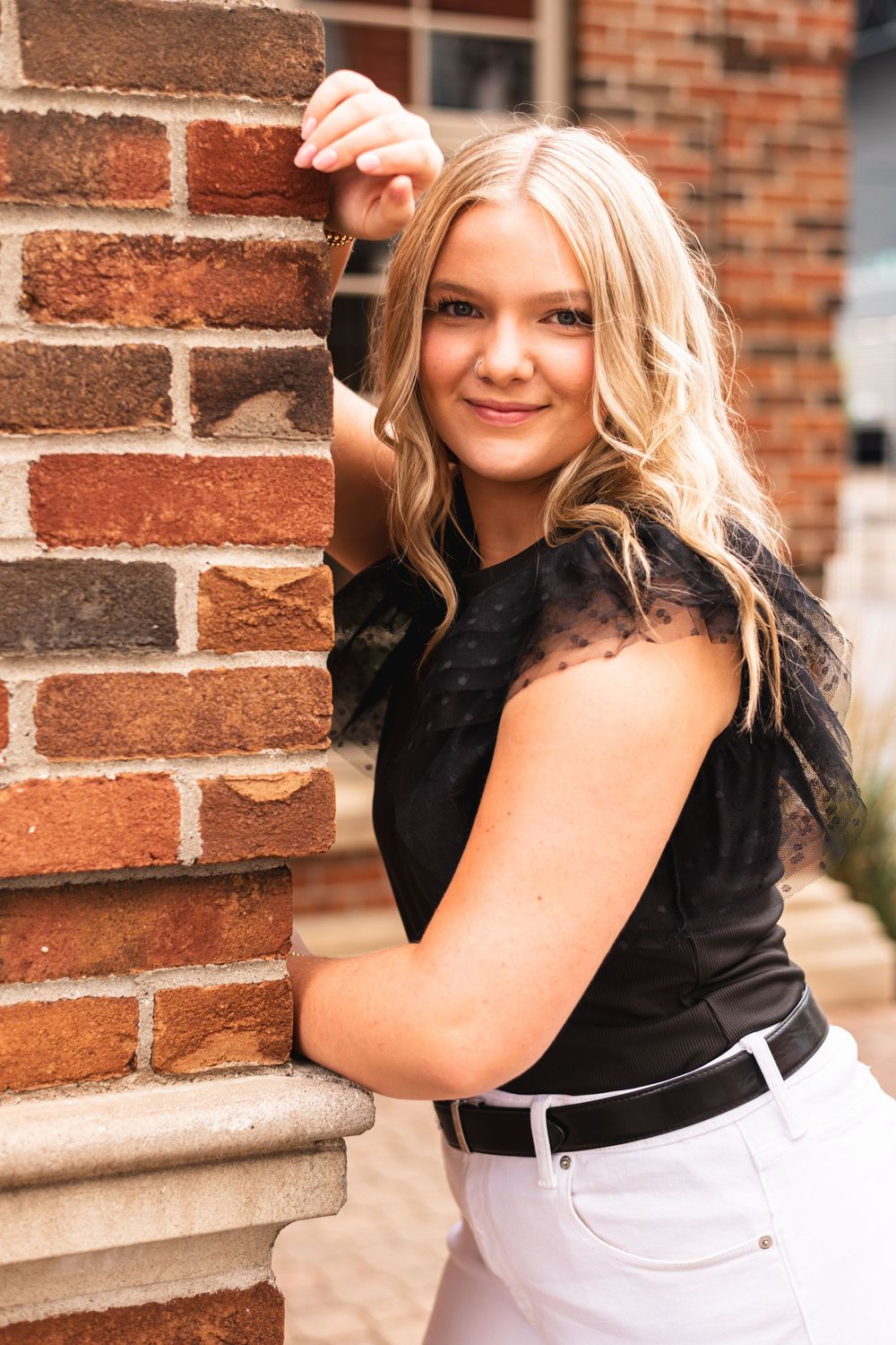 Senior girl leaning against a brick wall in downtown Grand Rapids.