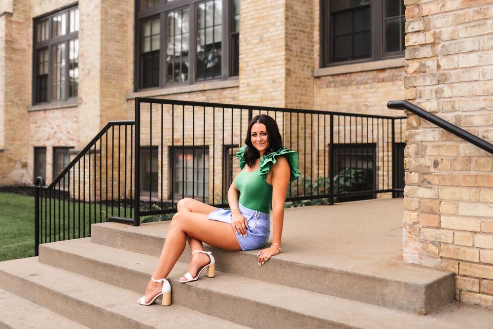Senior girl posing on the steps of a brick building in downtown Muskegon.